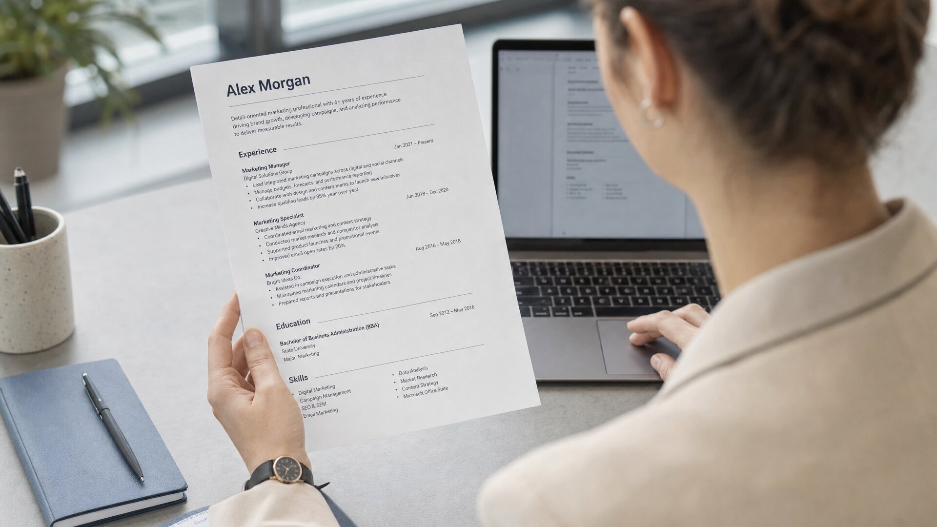 A recruiter scanning a printed CV, a watch on her wrist.